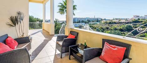 A balcony with wicker furniture, a table, and a bottle of champagne.