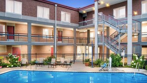 Un edificio de varios pisos con piscina, mobiliario exterior y una escalera.