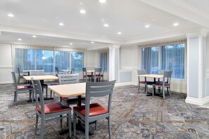 A dining area with tables and chairs, large windows with curtains, and a tiled floor. - Red Roof Inn Auburn Hills (Auburn Hills)