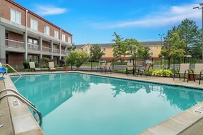 A swimming pool with lounge chairs and a fence, surrounded by a brick building with balconies. - Red Roof Inn Auburn Hills (Auburn Hills)