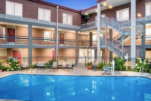 A multi-story building with a swimming pool, outdoor seating, and a staircase. - Red Roof Inn Auburn Hills (Auburn Hills)
