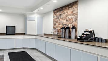 A modern kitchen with a stone accent wall, built-in cabinets, and a coffee station.