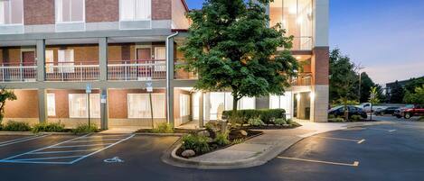 A Red Roof Inn with a two-story building, a parking lot, and a landscaped area with a tree.