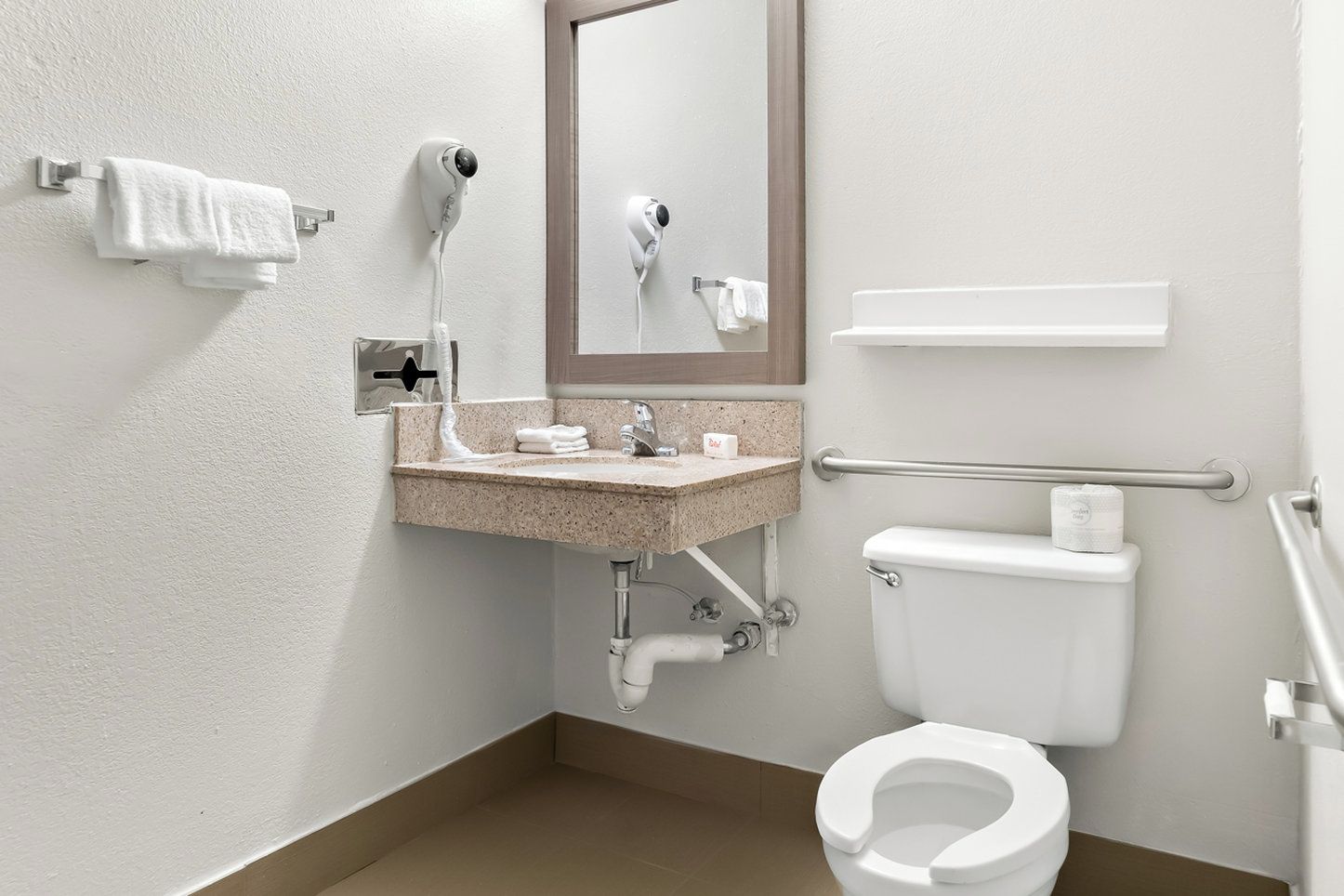 A modern bathroom with a sink, mirror, toilet, and towel rack.