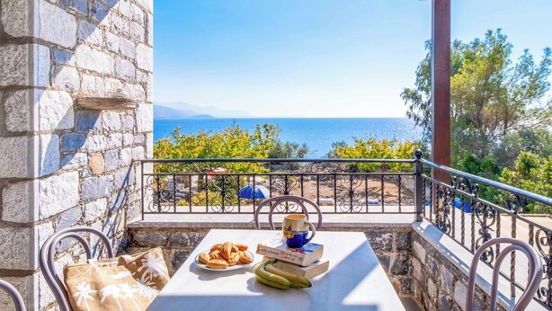 Ein Balkon mit Steinmauer, Tisch mit Büchern, Teller mit Keksen und Bananen.