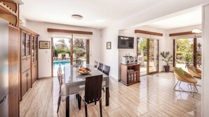 Uma cozinha ampla com área de refeições, vista para a piscina e televisão.