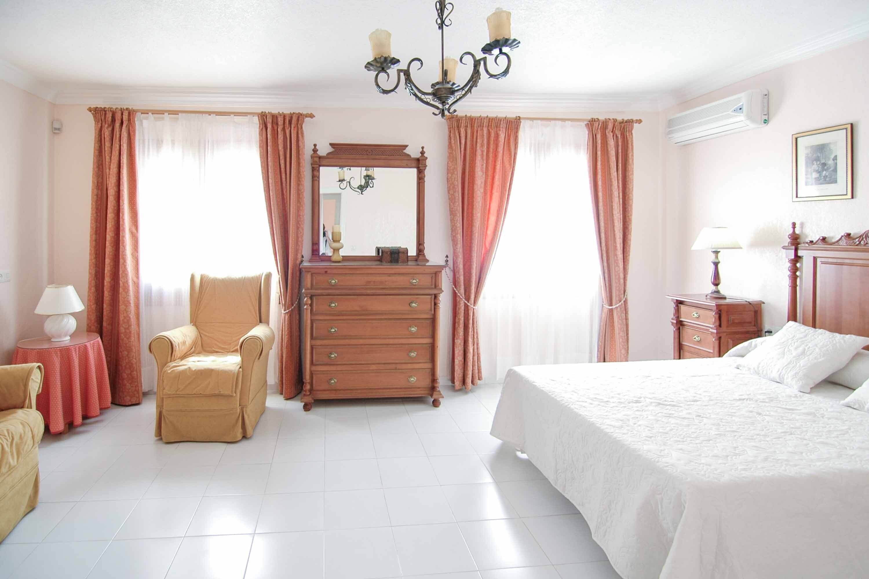 A hotel room with a bed, a chair, a dresser, and a mirror.