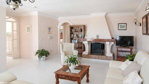 A spacious living room with a sofa, a coffee table, a fireplace, a television, and a bookshelf. - Villa Nerja Angeles - Three Bedroom Villa, Sleeps 6 (Nerja)