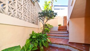 A narrow, tiled corridor with a decorative wall, a staircase, and potted plants. - Villa Nerja Angeles - Three Bedroom Villa, Sleeps 6 (Nerja)