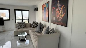 Una sala de estar moderna con un sofá modular, una mesa de centro y dos grandes cuadros abstractos en la pared.