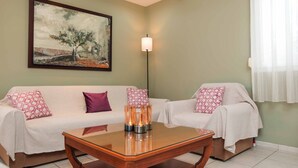A living room with two sofas, a coffee table, a floor lamp, and a painting on the wall.
