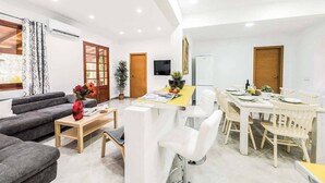 A modern living room with a sofa, coffee table, and dining area with chairs and a table. - Ca na Tonina - Five Bedroom Villa, Sleeps 10 (Pollença)