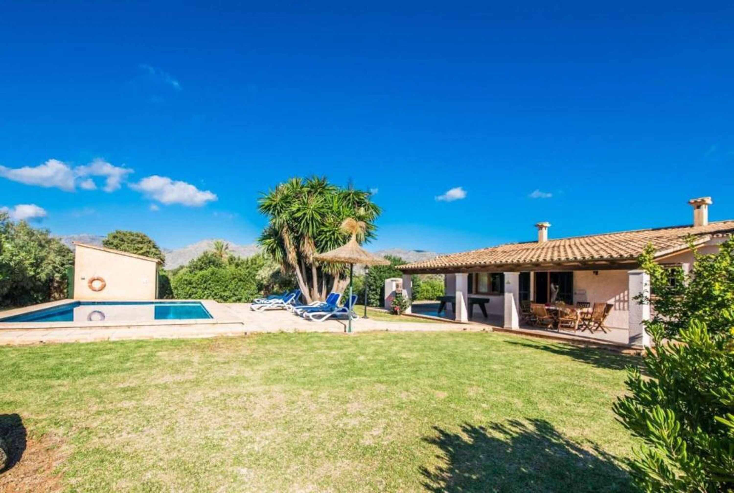 A house with a swimming pool, a patio with chairs, and a garden.