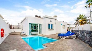 Une maison moderne dotée d’une piscine, d’un patio couvert et d’une bouée de sauvetage fixée au mur.