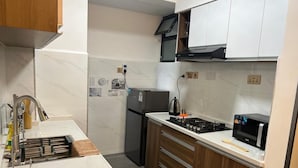 Une cuisine moderne dotée d’un plan de travail en marbre, d’appareils électroménagers en acier inoxydable et de meubles de rangement en bois.