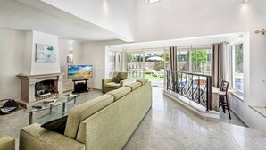 Un salon spacieux doté d’une cheminée, de sièges confortables et de grandes fenêtres offrant une vue sur l’extérieur.