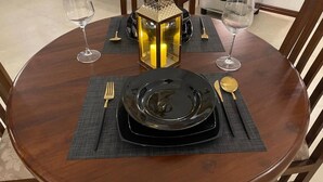 Une table de salle à manger ronde, avec une assiette noire, des couverts dorés et un chandelier.