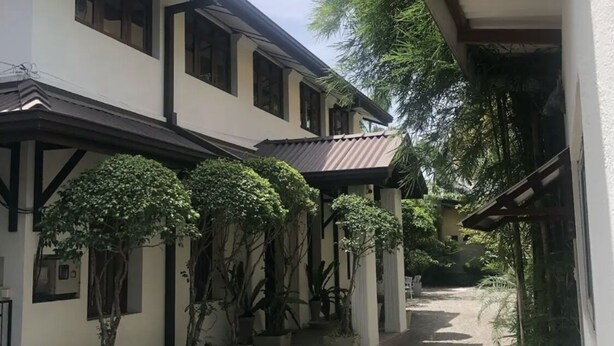 Un bâtiment doté d’une allée couverte, de plantes en pot et d’un chemin de gravier.