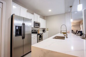 A modern kitchen with a stainless steel refrigerator, a microwave, and a large island with a sink. - 8952 Private Pool Townhome Near Disney - Paradise Palms (Kissimmee)