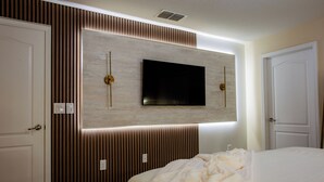 Ein Hotelzimmer mit einem großen Bett, einem an der Wand befestigten Fernseher und einer Wandpaneel-Gestaltung.