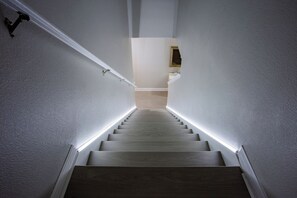 Una escalera con barandilla y una tira de luz a lo largo de los peldaños.