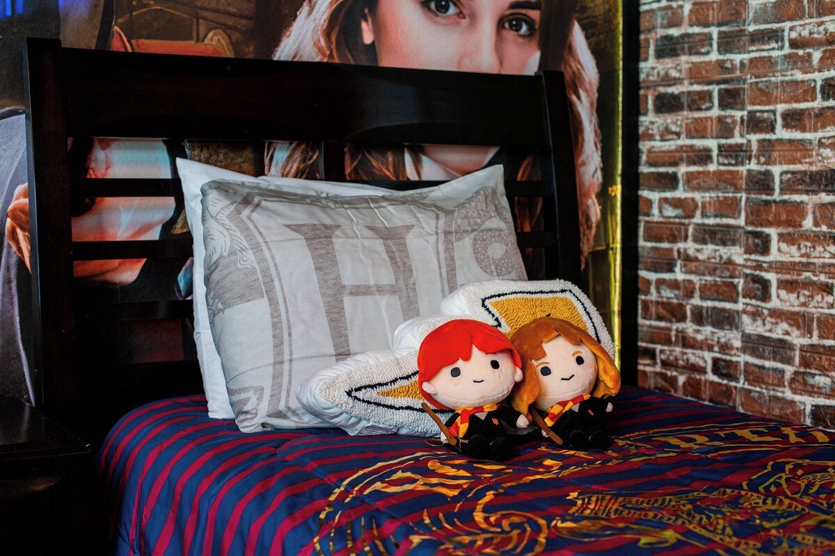 A bed with a patterned bedspread, pillows, and two plush toys on a headboard.