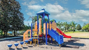 Une aire de jeux avec un toboggan, des structures d’escalade et un espace de jeux couvert.