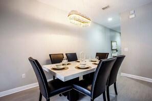 A dining area with a marble table, black upholstered chairs, and a chandelier. - 8952 Private Pool Townhome Near Disney - Paradise Palms (Kissimmee)