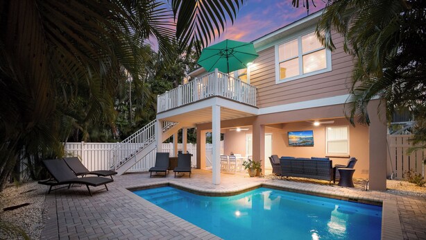 Une maison à deux étages dotée d’une piscine, de mobilier d’extérieur et d’un patio couvert.