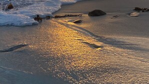 Ein Strand mit Wellen und einem Sonnenuntergang.