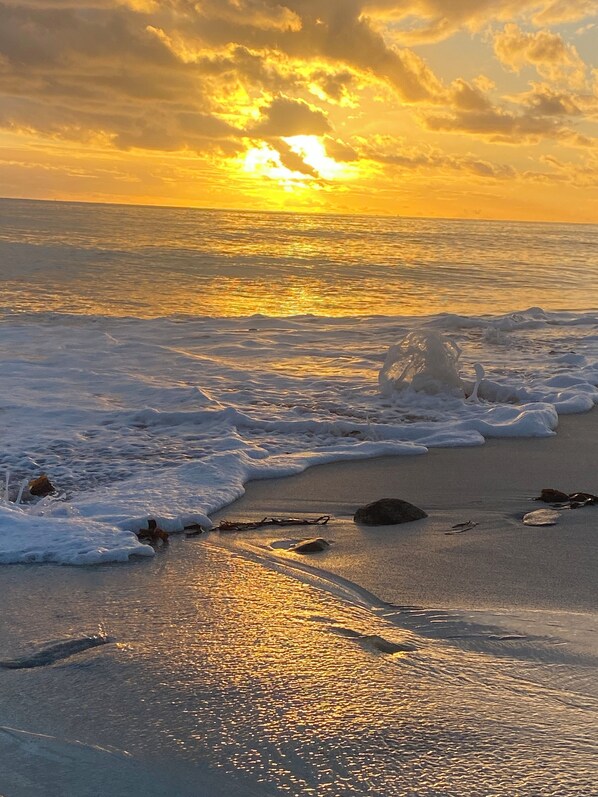 A beach with waves and a sunset.
