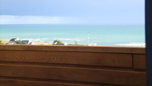 Blick auf den Ozean durch ein Fenster mit Holzjalousien.