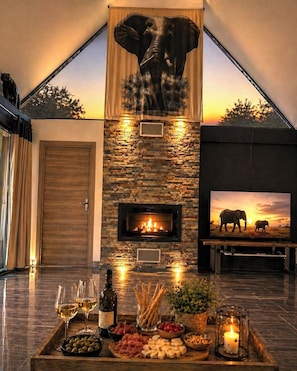 Una habitación con chimenea, televisión y una bandeja con aperitivos y bebidas.