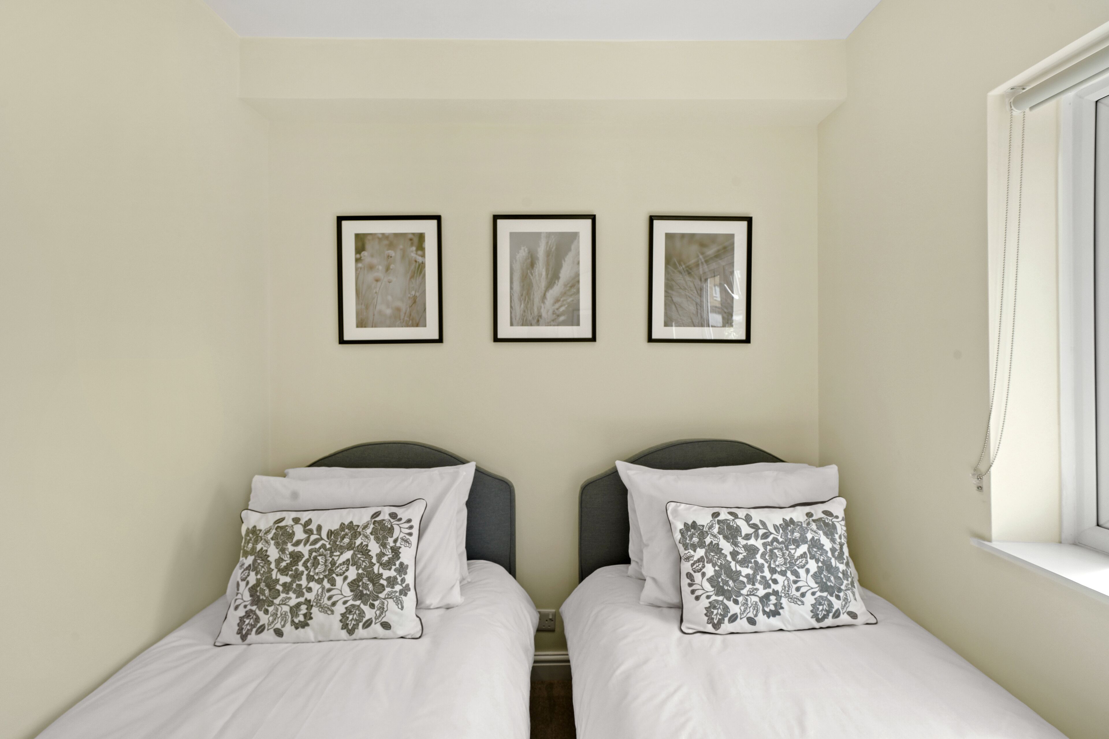 A room with two beds, each with a pillow and a framed picture above.