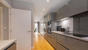 A modern kitchen with a wooden floor, stainless steel appliances, and a white door. - Stunning Townhouse XII - Cosy but spacious home from home stays, all in one. (London)