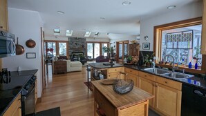 Una cocina amplia con armarios de madera, una isla central y un gran ventanal con vista a árboles.