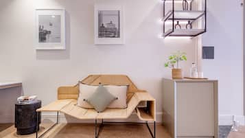 A room with a rattan sofa, a small round table, and a minimalist shelving unit.