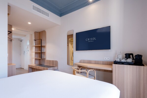 A hotel room with a bed, a desk, a chair, a TV, and a wardrobe. - Crisol Mozart (Nice)
