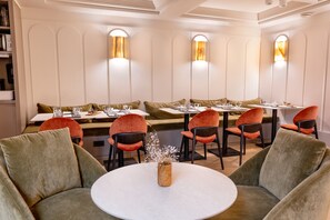 A restaurant with round tables, cushioned seating, and wall-mounted lighting. - Crisol Mozart (Nice)