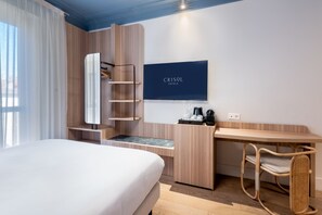 A hotel room with a bed, a desk, a chair, a TV, and a wardrobe. - Crisol Mozart (Nice)