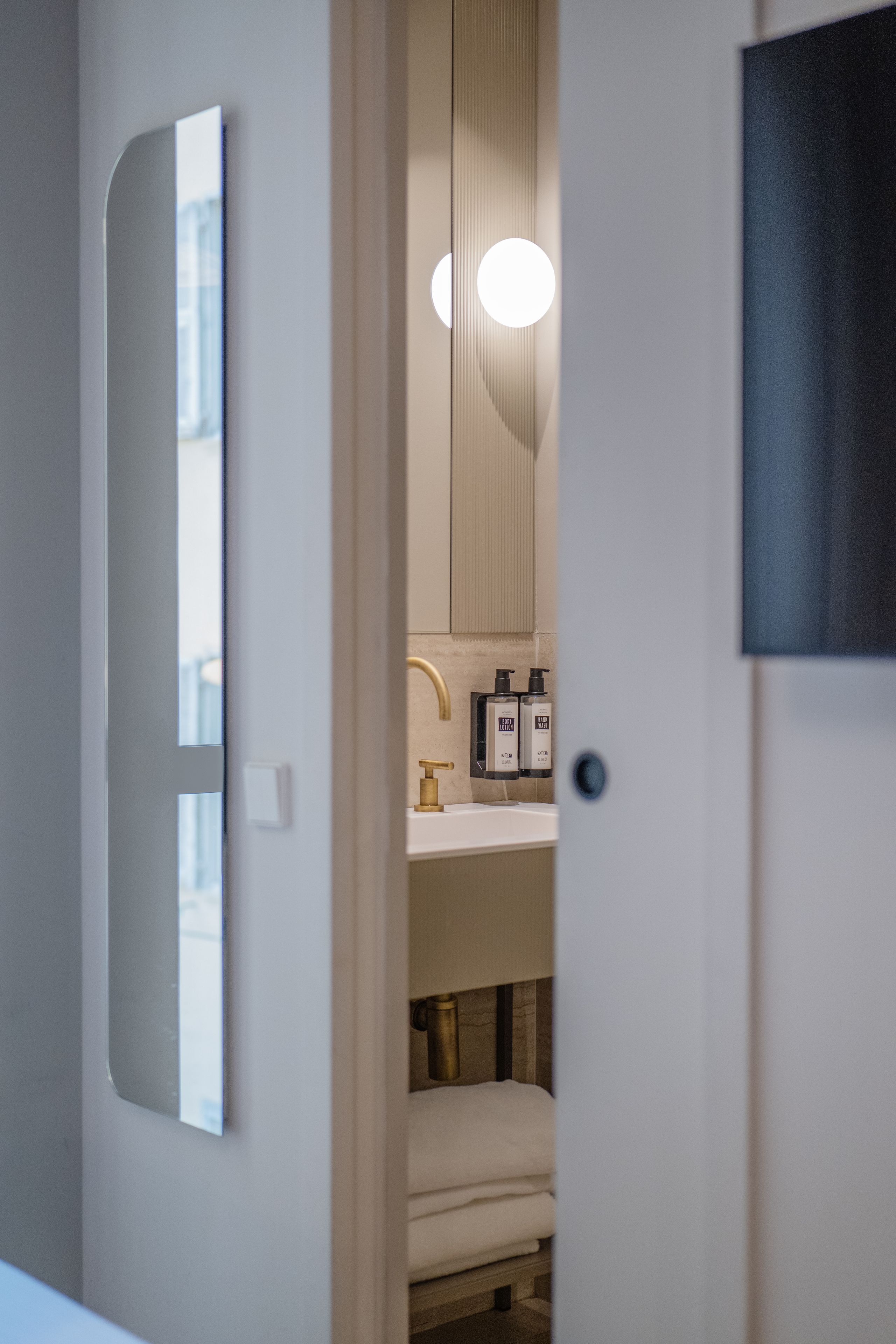 A bathroom with a mirror, a sink, and a towel rack.