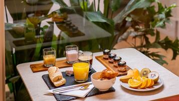 Een ontbijttafel met diverse soorten eten en drinken, waaronder een croissant, oranjes en een glas sinaasappelsap.