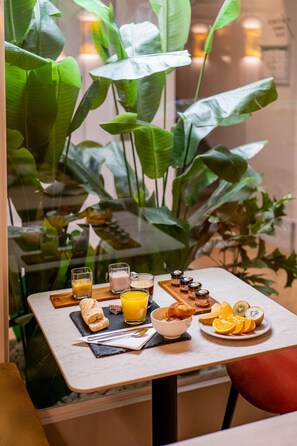 A breakfast table with a variety of food items and drinks, including a croissant, orange slices, and a glass of orange juice. - Crisol Mozart (Nice)