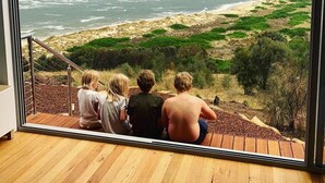 A room with a large window overlooking a beach and ocean. - Three Little Birds at Freycinet - Ocean views! (Glamorgan-Spring Bay)