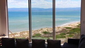 A room with a large window overlooking a beach and ocean. - Three Little Birds at Freycinet - Ocean views! (Glamorgan-Spring Bay)