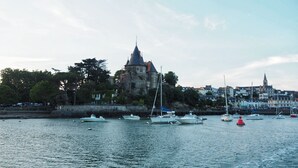 Un port avec des bateaux, un bâtiment qui ressemble à un château et une église en arrière-plan.