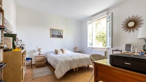 A bedroom with a bed, bedside table, lamp, and a desk with a printer.