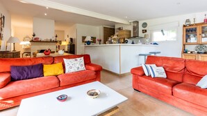 A living room with two red leather sofas, a white coffee table, and a kitchen area in the background.