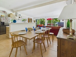 Une cuisine moderne avec un coin repas, un téléviseur et une grande fenêtre.