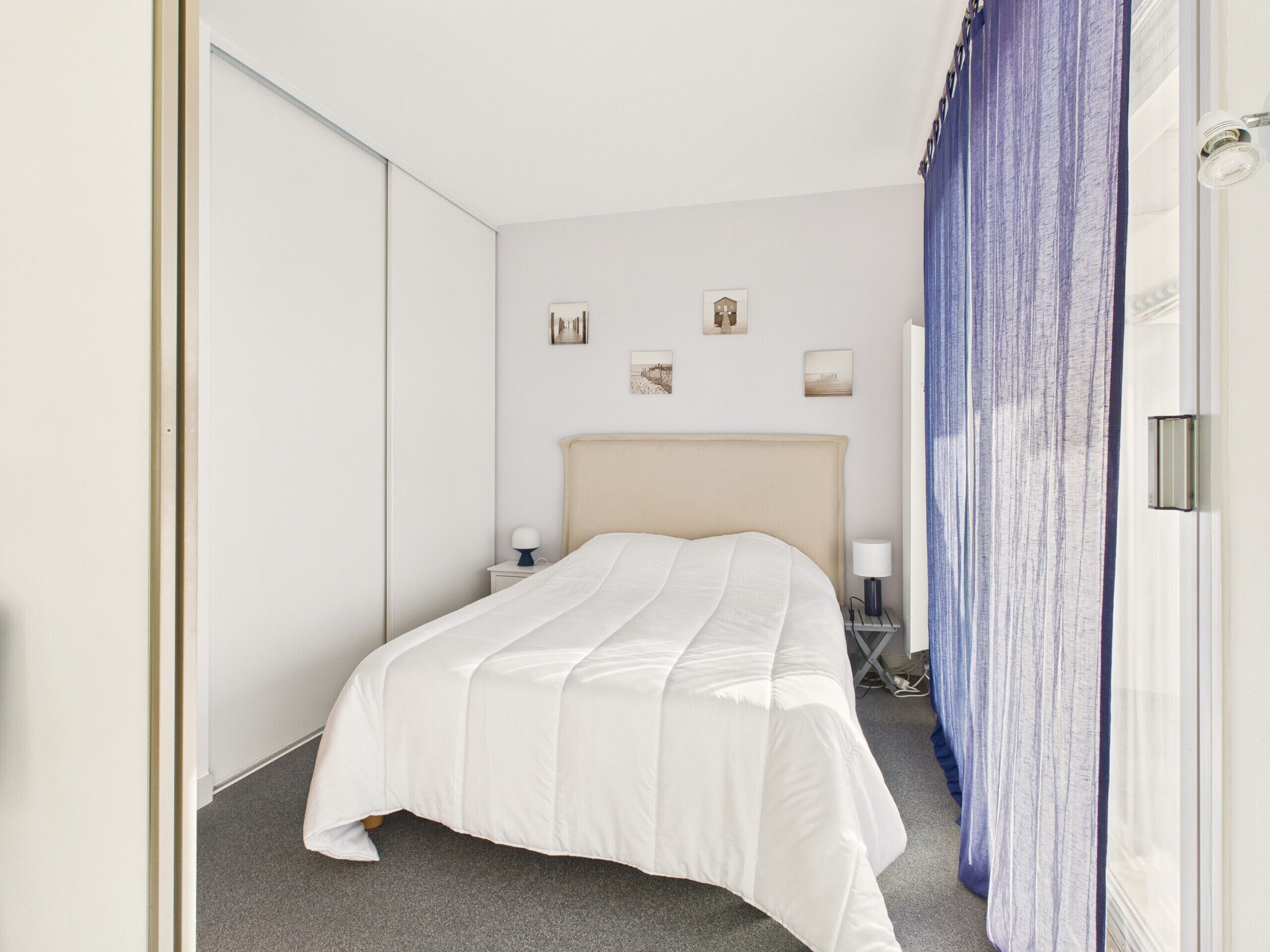 A hotel room with a bed, bedside tables, and a wardrobe.